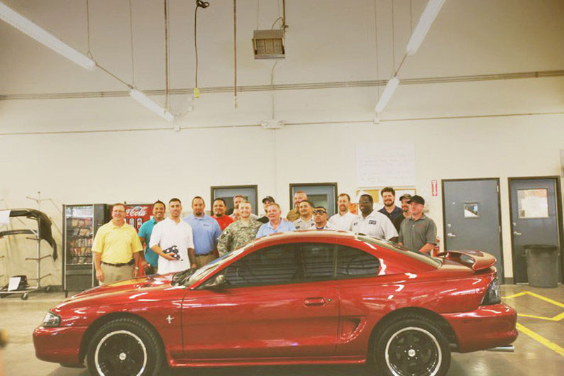 Continental Collision staff standing in front of red Ford Mustang