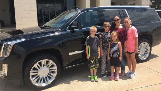 happy family infront of new Cadillac