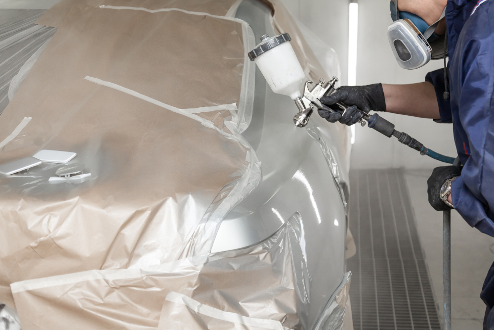 Auto body technician spraying car in paint booth